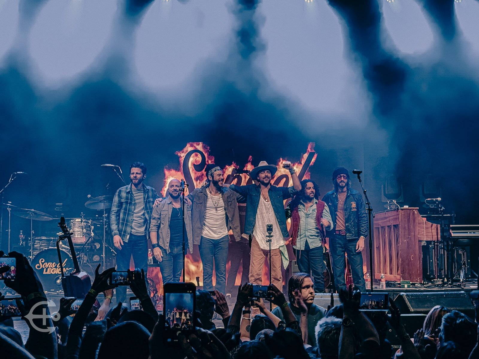 Performers taking a final bow beneath blue stage lights