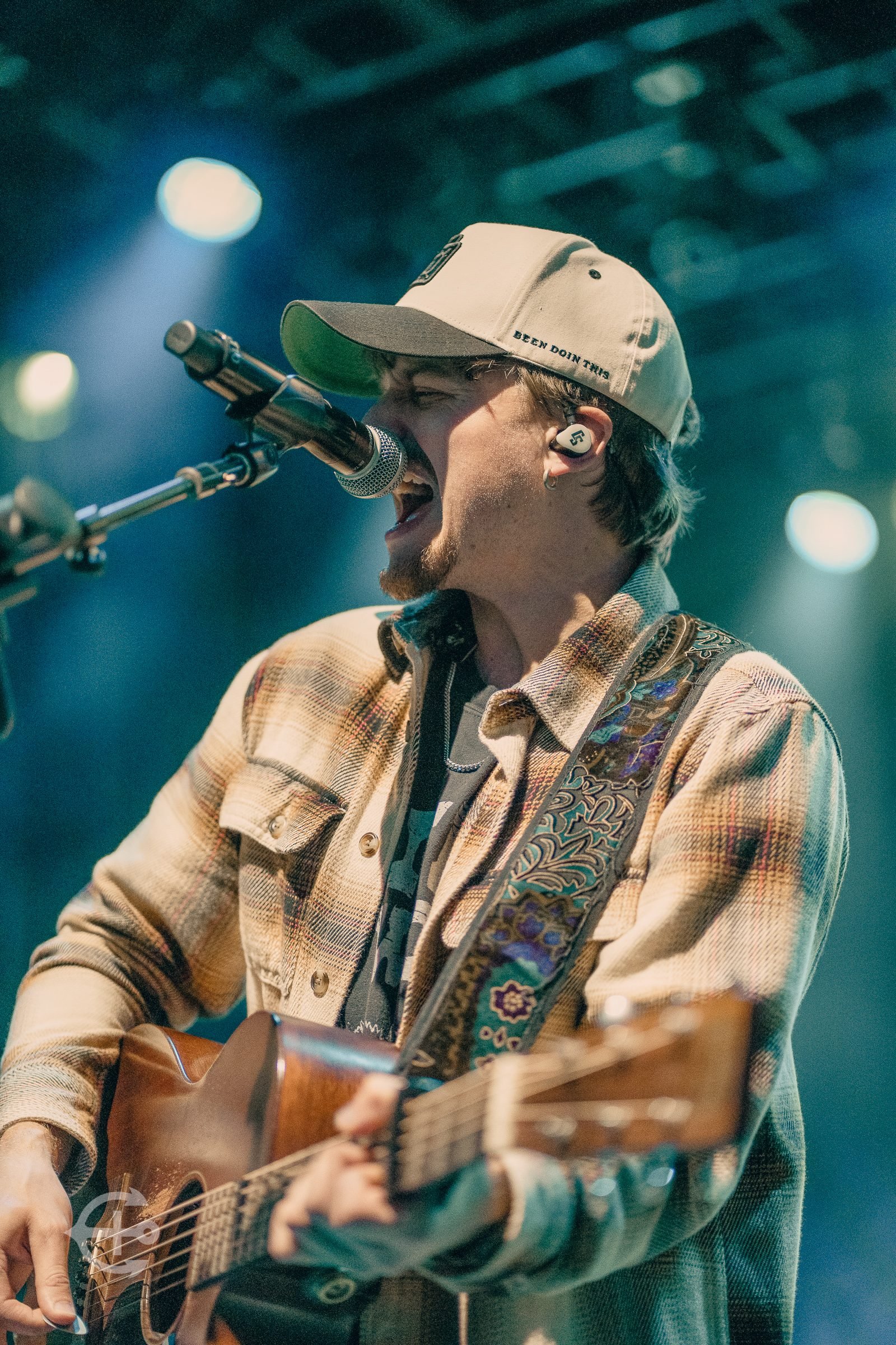 Singer and guitarist performing under teal stage lights