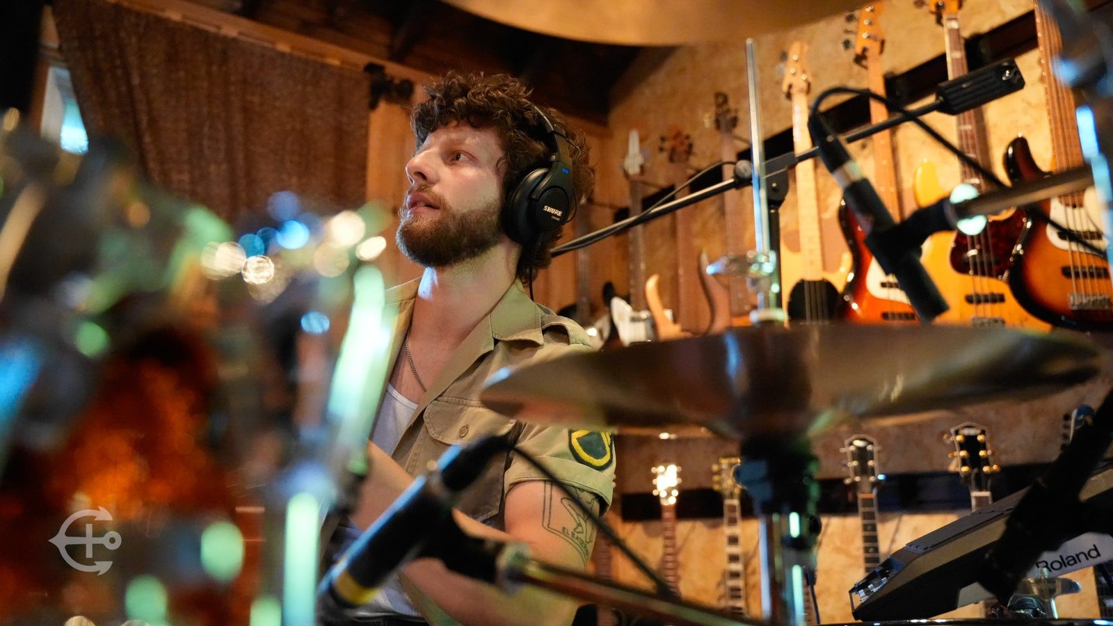 Drummer performing in a warm wood-paneled recording space