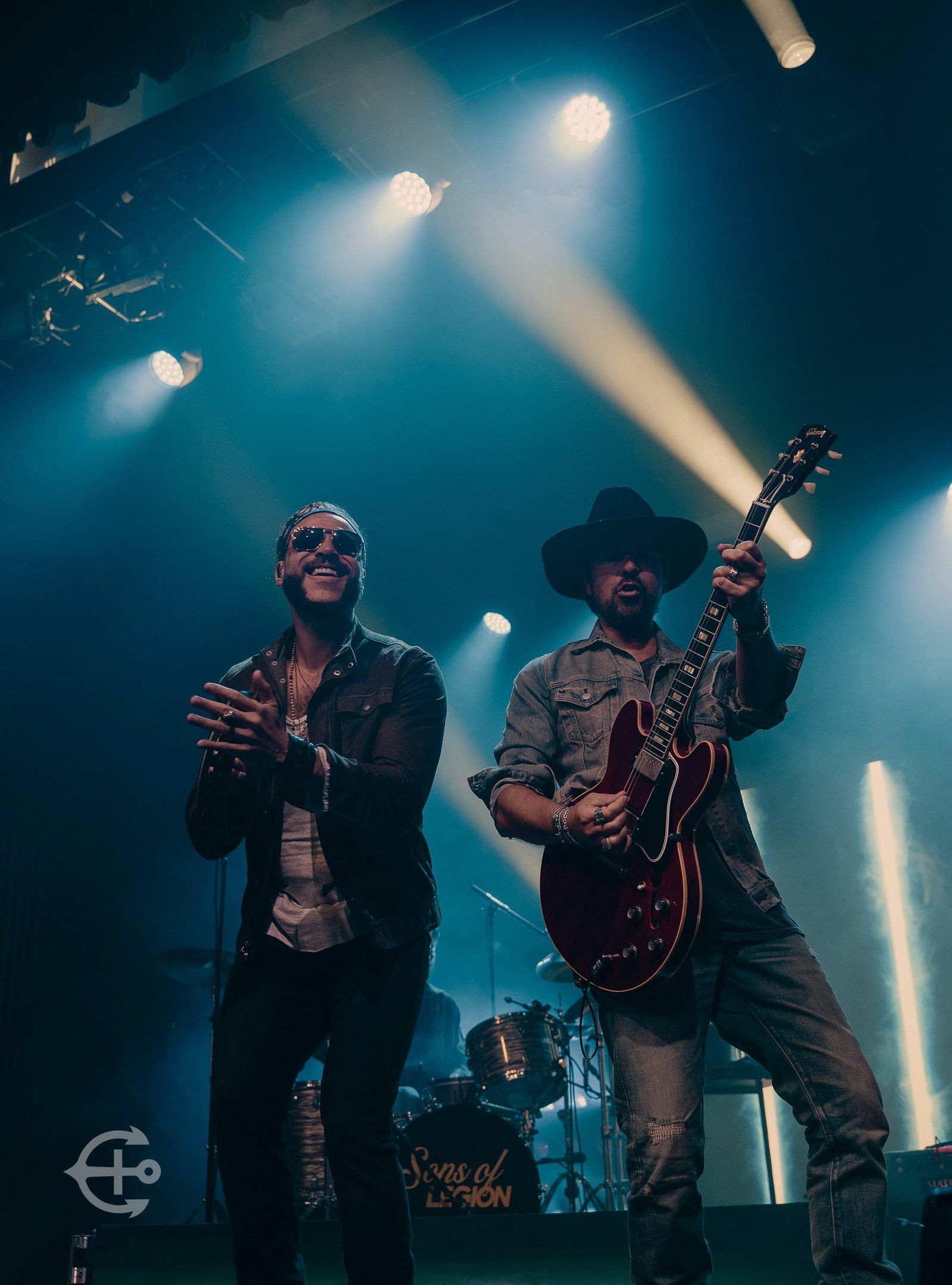 Two musicians sharing the stage under blue concert lights