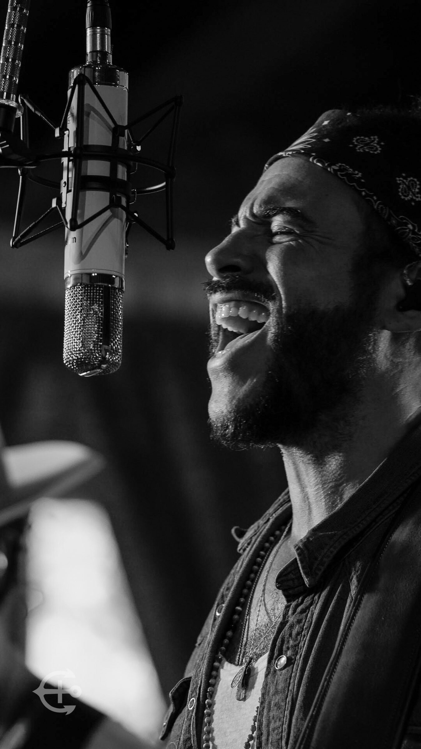 Black-and-white portrait of a vocalist singing into a studio microphone