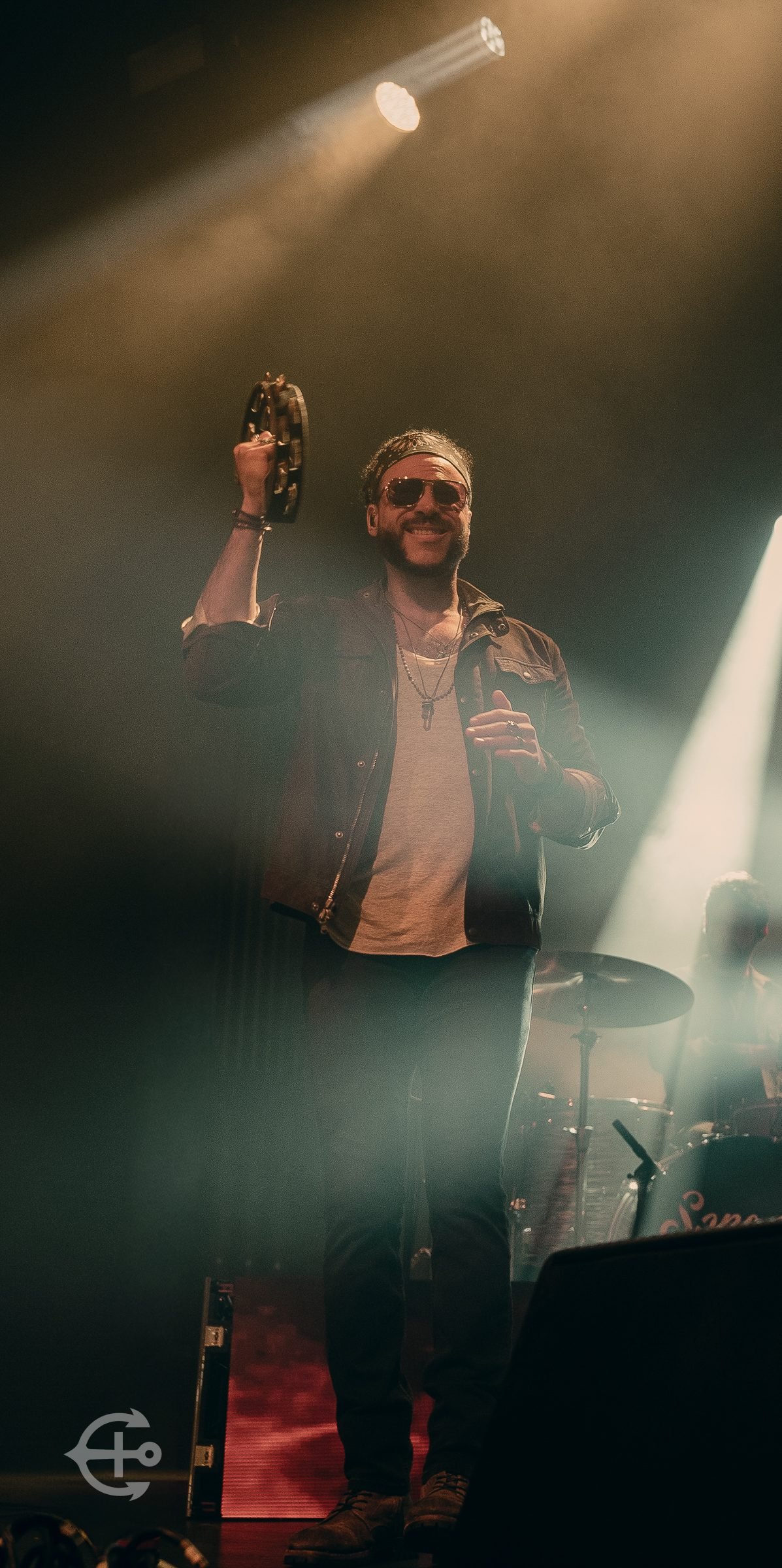 Performer raising a glass onstage beneath warm spotlights