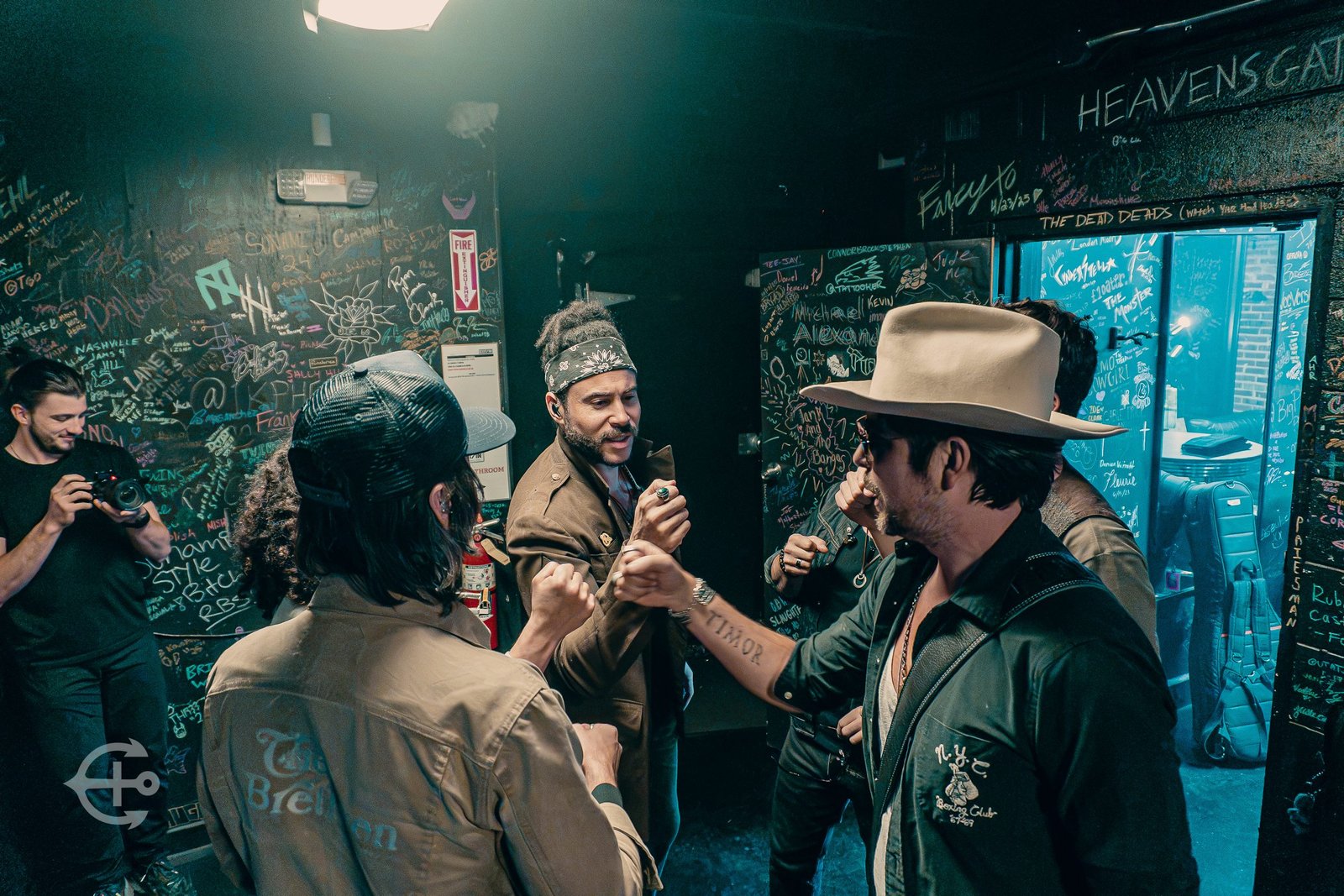 Musicians sharing a backstage toast in a signed venue room