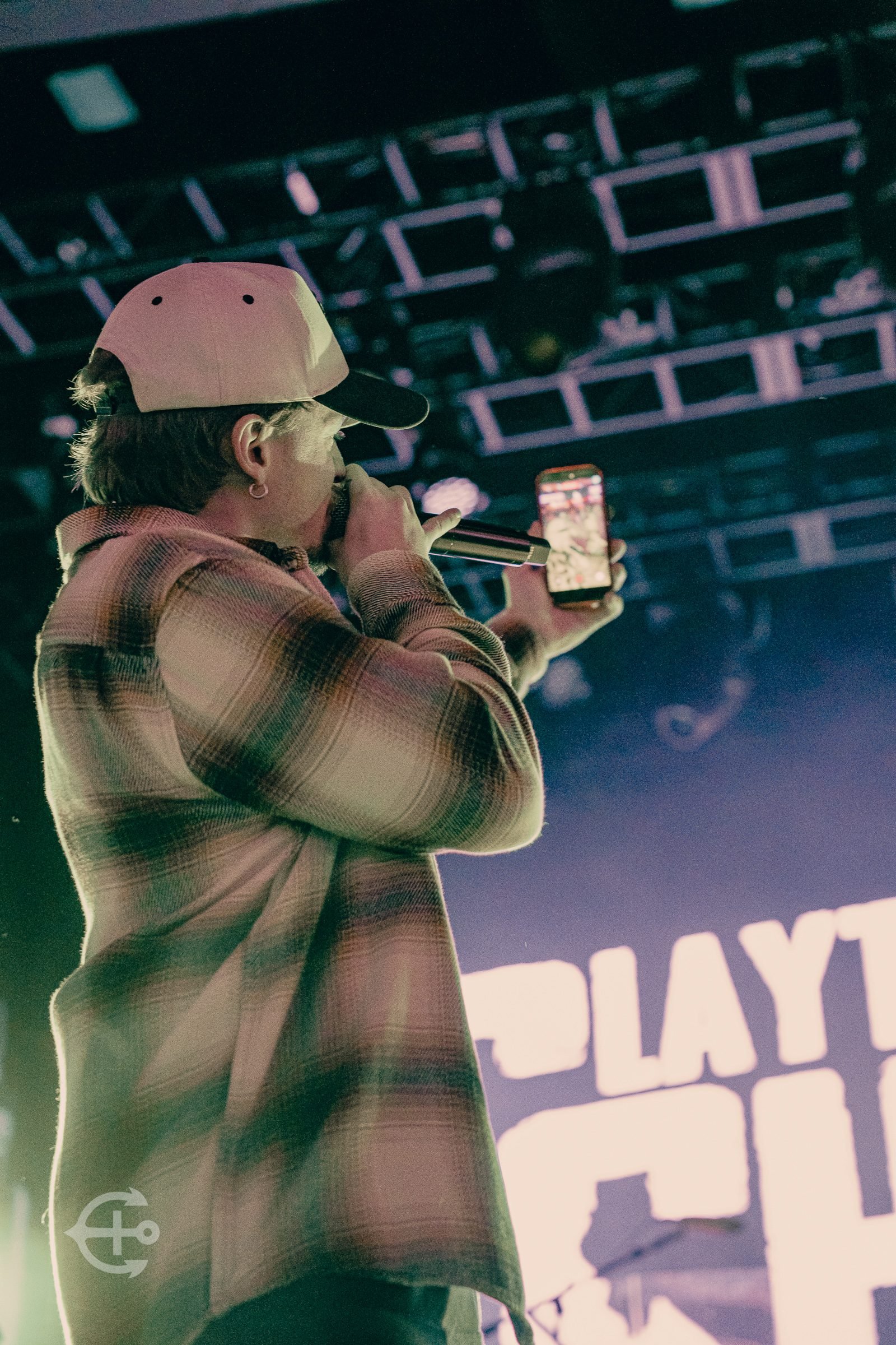 Vocalist performing in side profile beneath venue lighting