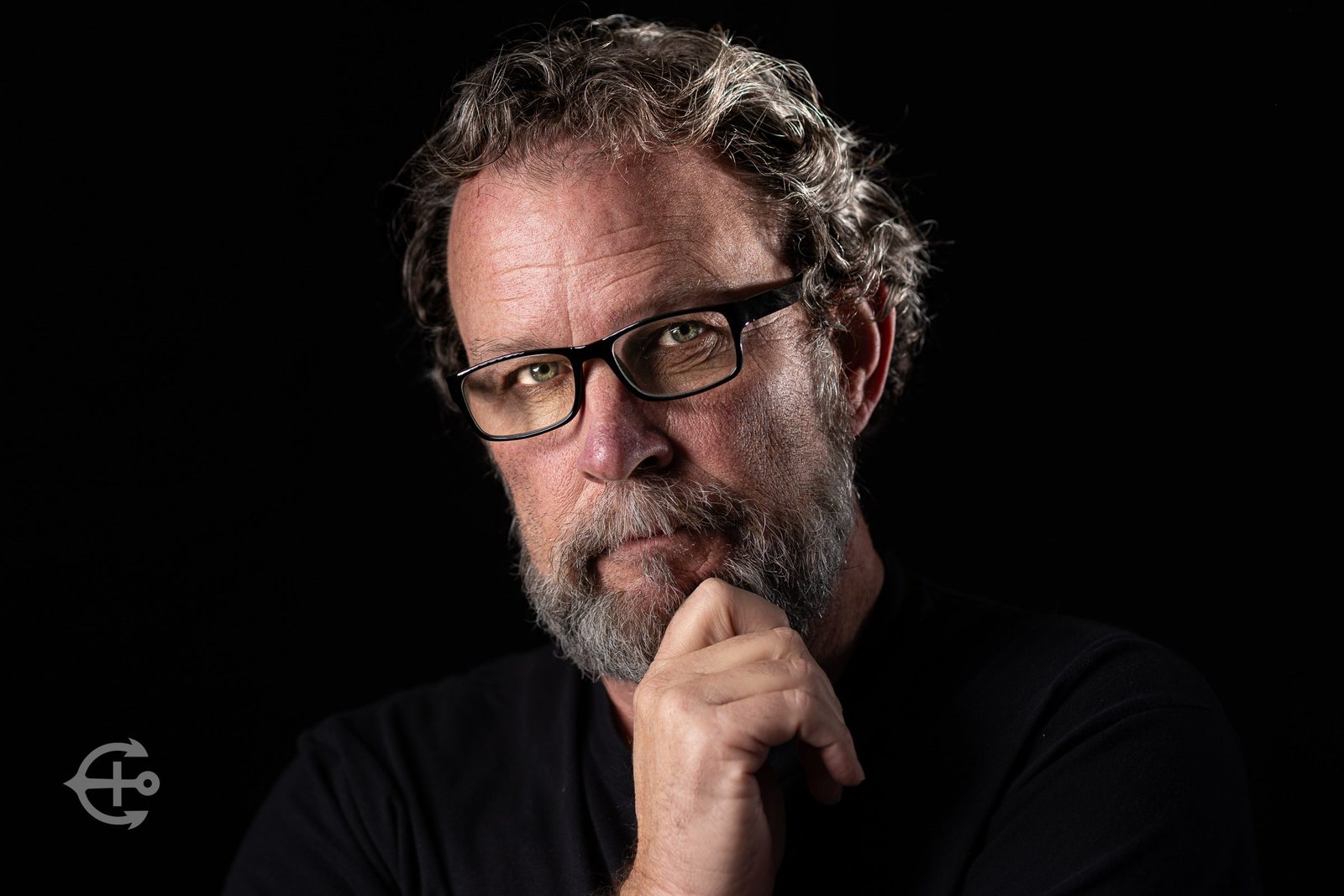 Dramatic studio headshot of a man with glasses