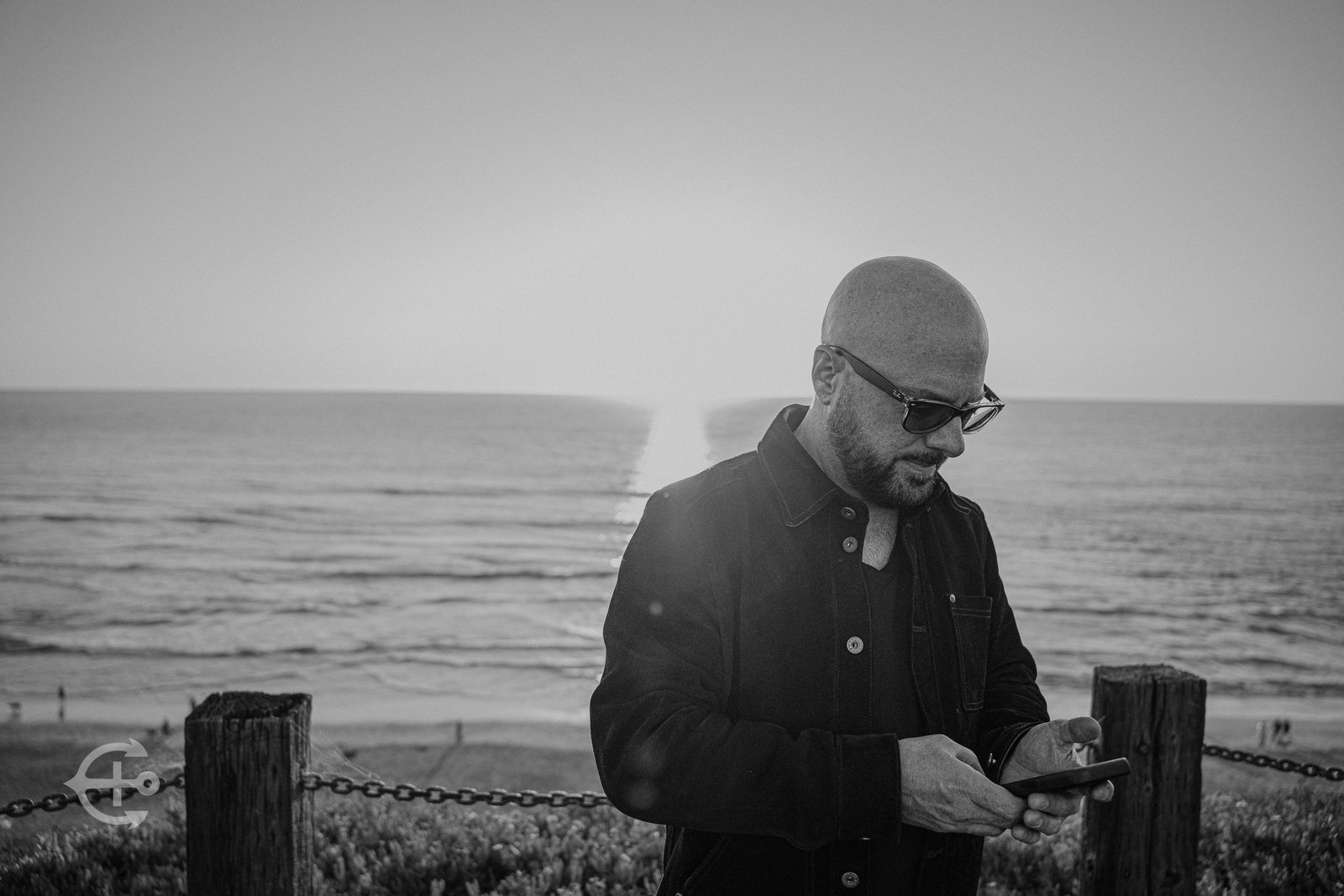 Artist standing near the coast in a black-and-white environmental portrait
