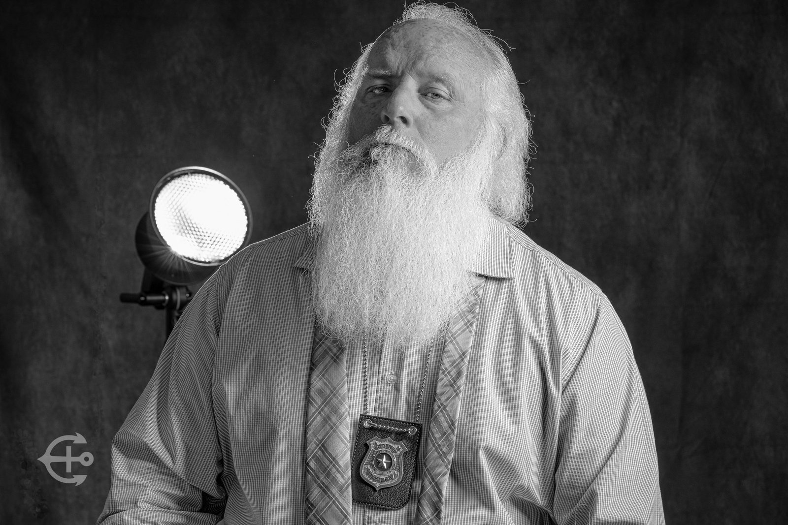 Black-and-white character portrait of a bearded man holding a vintage camera