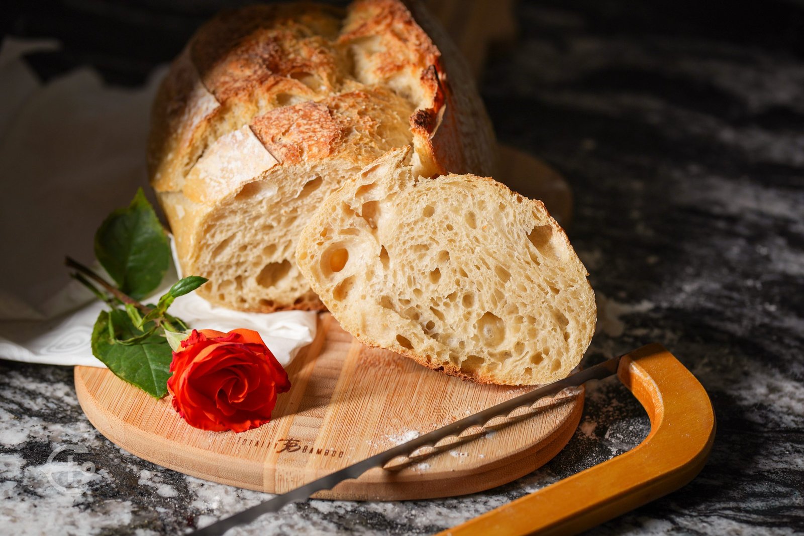Artisan bread arranged on a wooden board with a rose