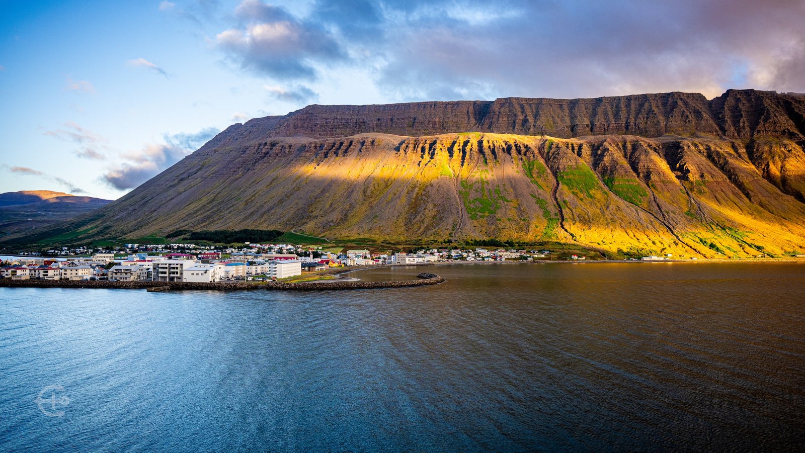 Ísafjörður waterfront beneath a mountain striped with golden sunlight