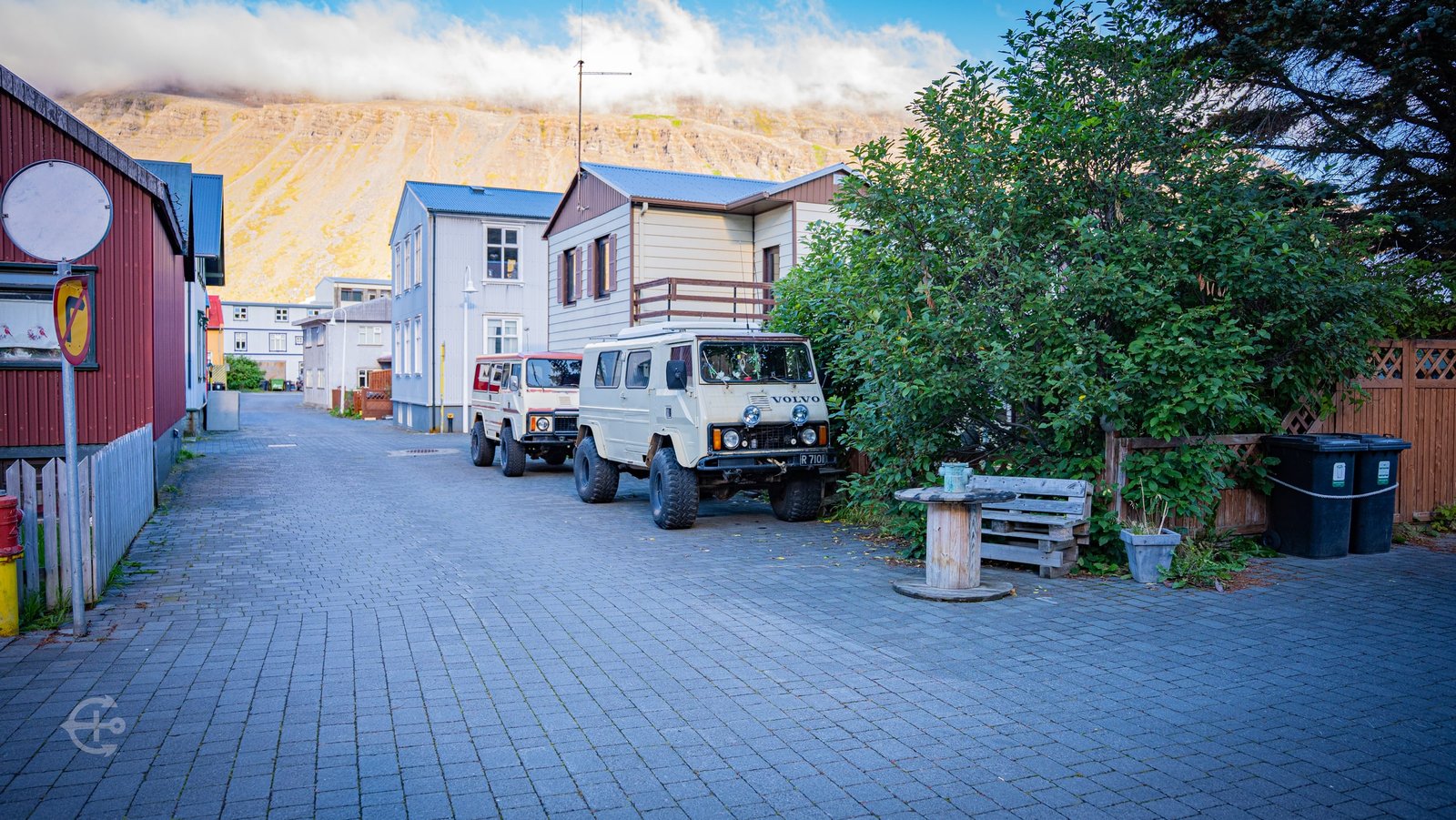 Two vintage off-road vehicles parked along a quiet town lane