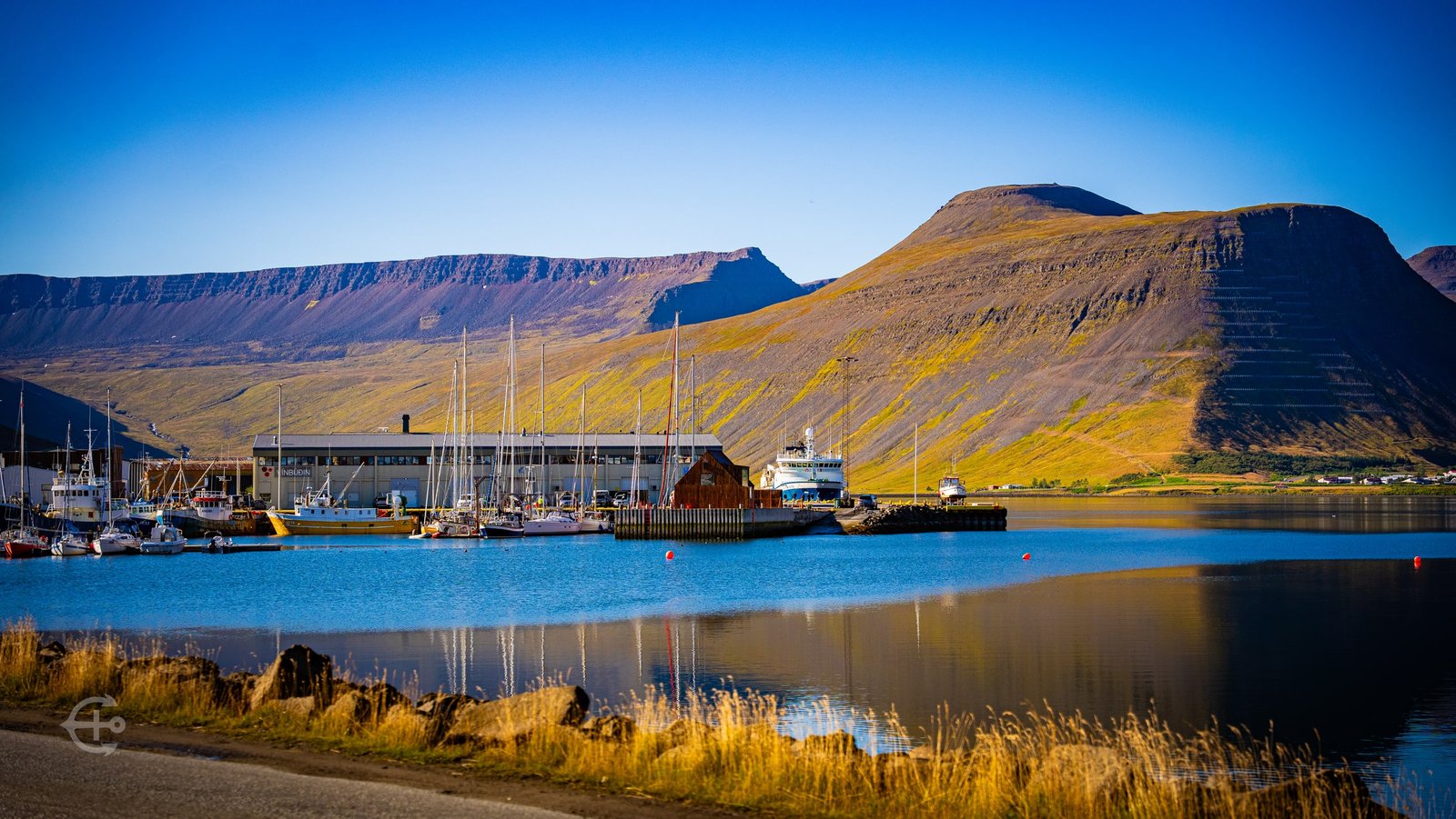 Sailboats and fishing vessels reflected in calm harbor water