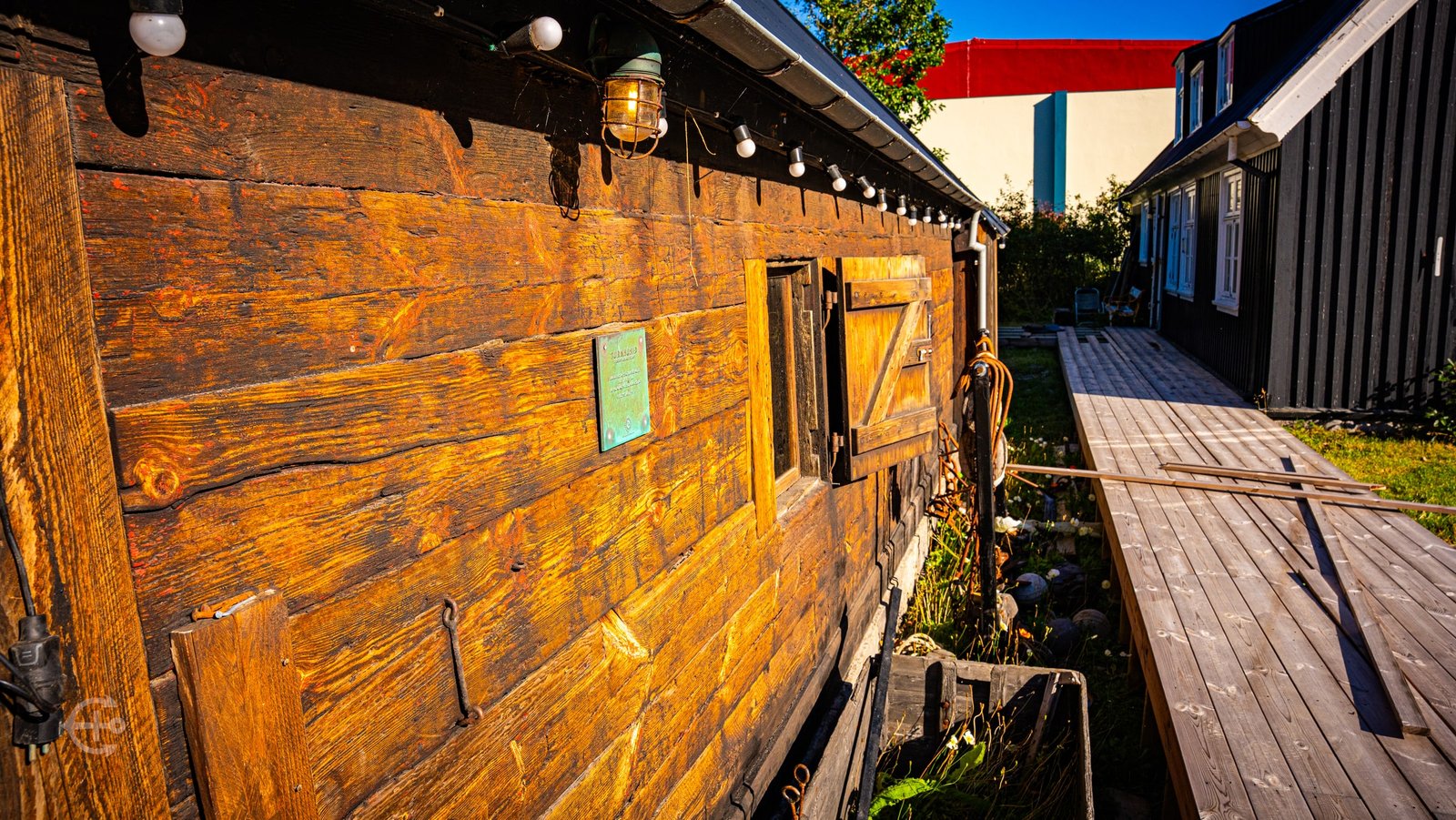 Sunlit timber wall and wooden walkway between historic buildings