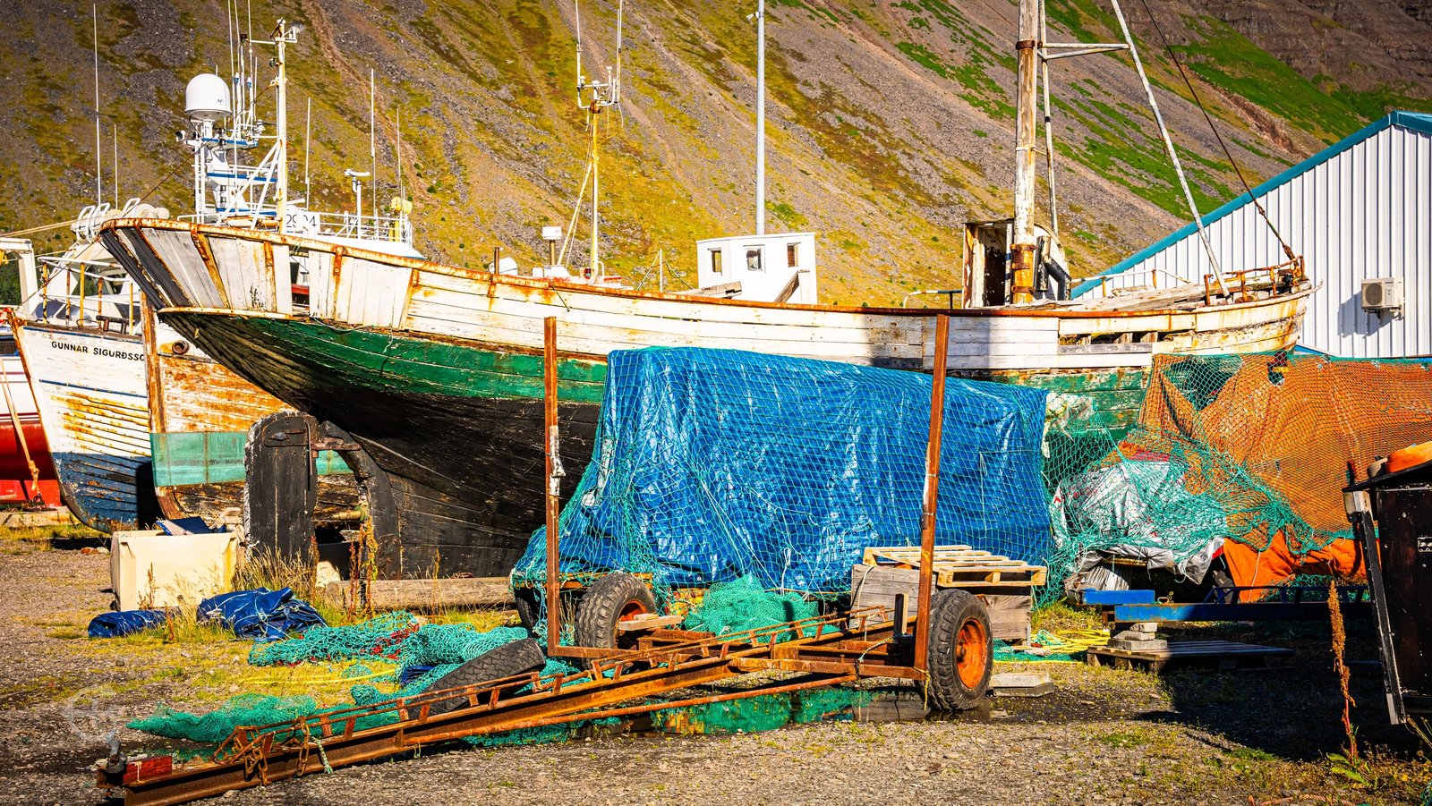 Weathered fishing boats and colorful nets in a boatyard