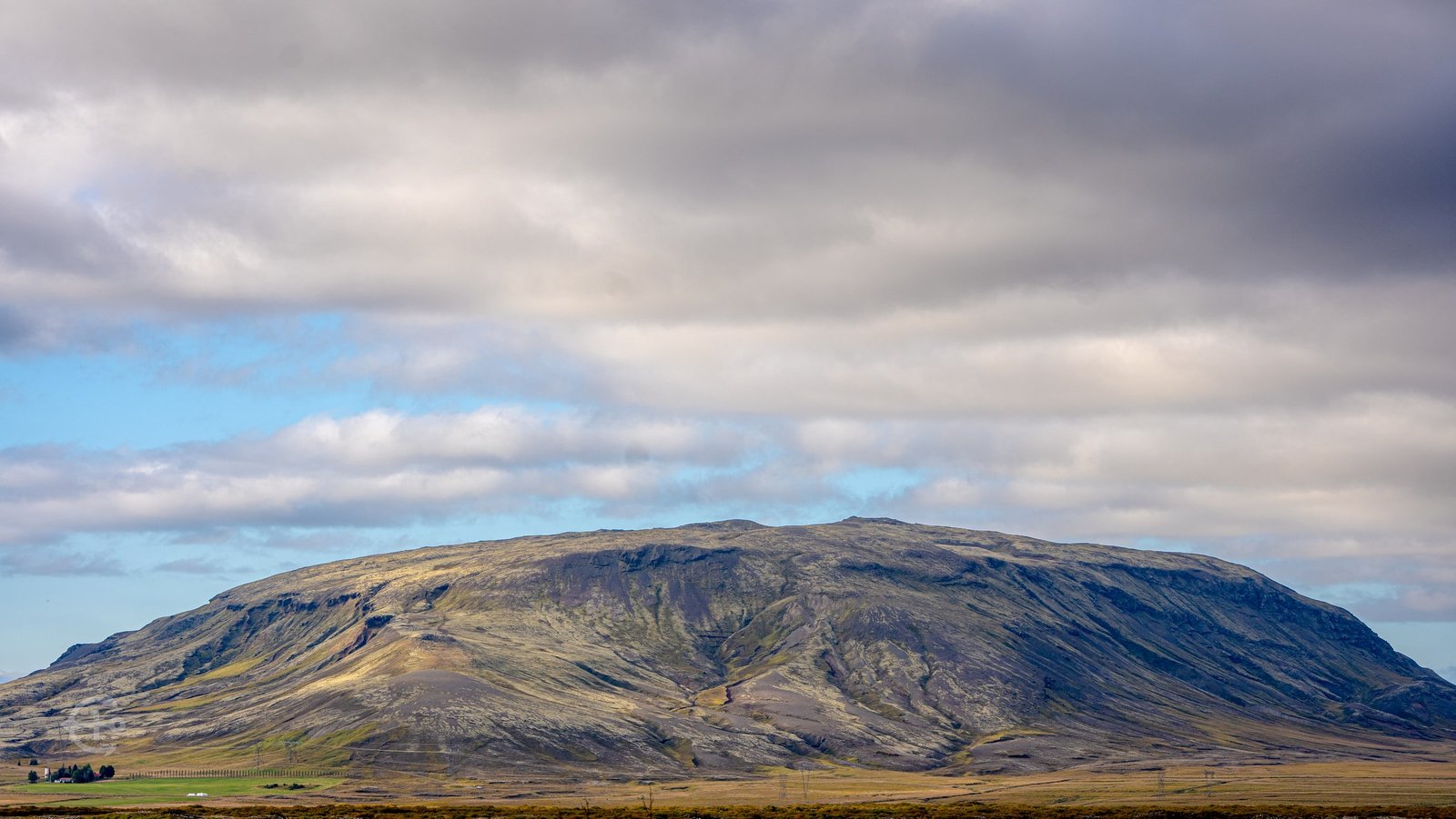 Broad mountain ridge beneath layers of gray cloud