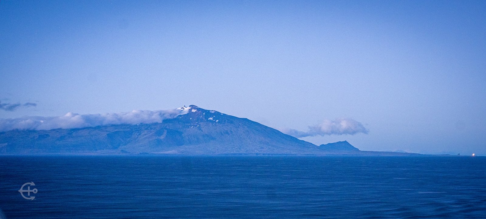 Blue coastal mountains seen across the sea at dusk