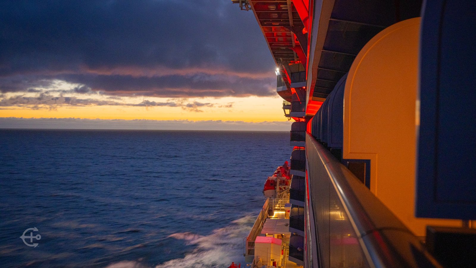 Sunset at sea beside the illuminated balconies of the cruise ship